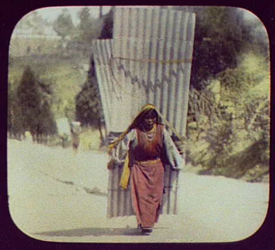 Woman carrying large corrugated sheets, India, 1895