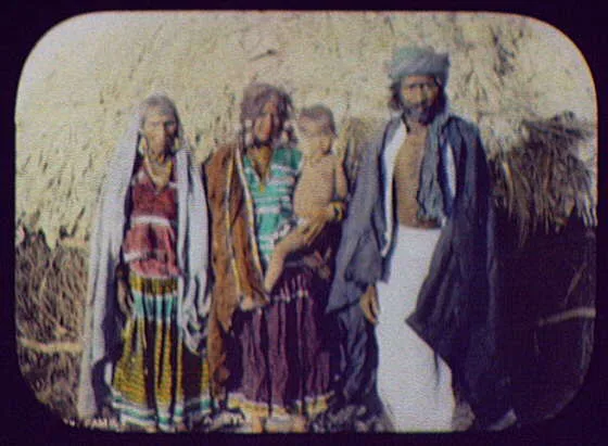 Family standing in front of thatched house, India, 1895
