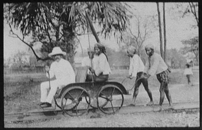 W.H. Jackson in railroad trolley car pushed by natives, Burma, 1895
