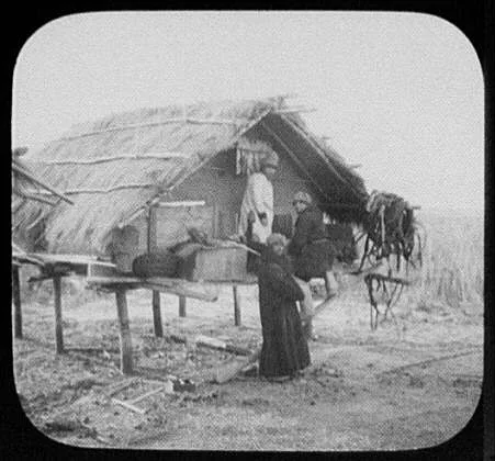 Three men at thatched-roofed store-house on stilts, Siberia, 1895